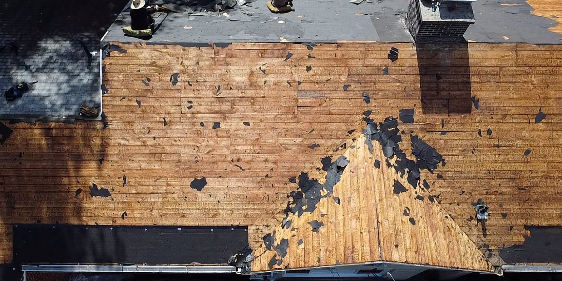 Same roof mid tear-off — stripped to bare plank decking